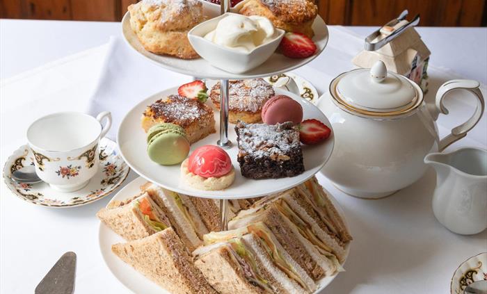 Indulge in a homemade ​luxury afternoon tea, featuring freshly baked scones with ​whipped cream and strawberry jam, ​delectable sandwiches​ and an ass